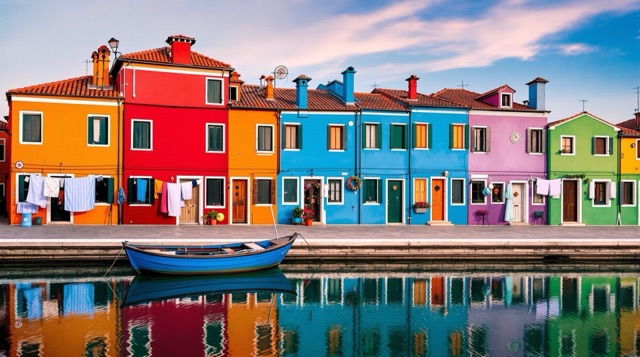 Colorful houses of Burano reflected in a still canal at dawn